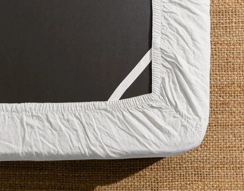 Le dessous d'un matelas équipé de notre Signature European Linen Fitted drap en blanc pour montrer l'élastique Stay Snug qui le maintient en place.