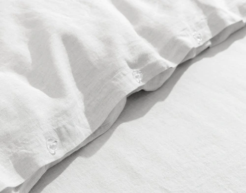 Gros plan sur notre housse de couette Signature European Linen en blanc pour montrer sa fermeture à boutons classique.