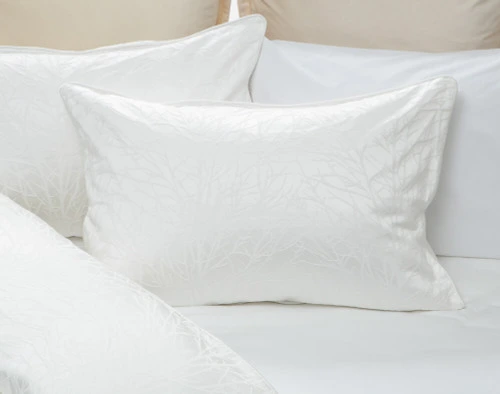 Notre modèle Blanchard White Pillow Sham sur une literie blanche.