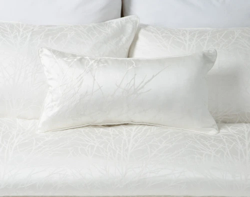 Notre housse de coussin Blanchard White Boudoir sur une literie blanche.