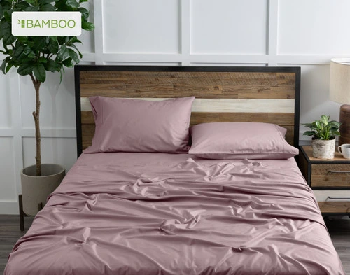 Vue du dessus de notre Bamboo Cotton drap  ensemble  en Orchid Purple habillé au-dessus d'un lit en bois dans une chambre à coucher remplie de plantes blanches.