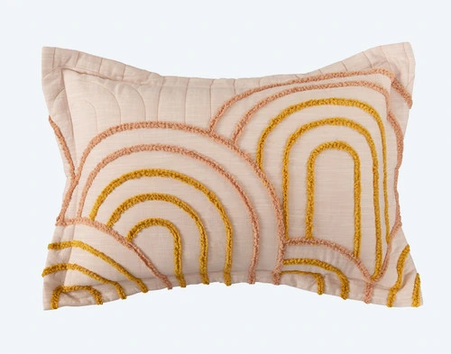 Notre modèle Maeve Pillow Sham est doté d'un bord à rebord léger et d'un touffetage circulaire orange sur un fond blanc.