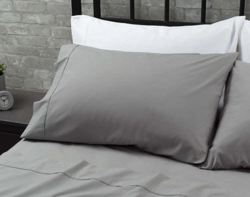 Les taies d'oreiller de notre Coton Percale drap ensemble  en gris reposant contre deux oreillers blancs au sommet d'un grand lit.