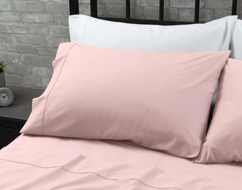 Les taies d'oreiller de notre Coton Percale drap ensemble  en Lilas reposant contre deux oreillers blancs en haut d'un grand lit.