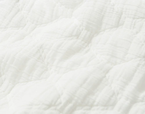 Gros plan sur le tissu texturé en coton blanc de notre Cavell White Cotton courtepointe ensemble .