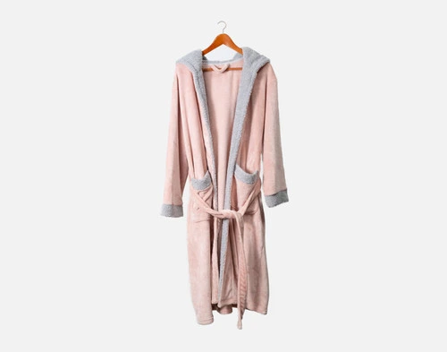 Notre peignoir polaire Boucle en rose blush suspendu à un cintre sur un fond blanc.