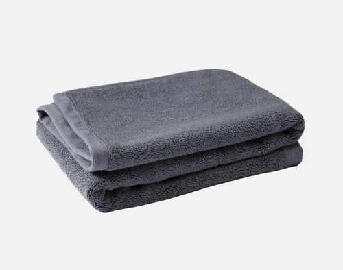 Pile pliée de notre tapis de bain en coton modal Stormcloud sur un fond blanc uni.