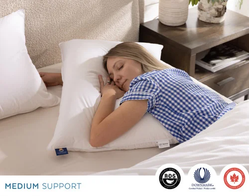 Woman resting on her stomach with her face turned on our Opula Down Pillow.