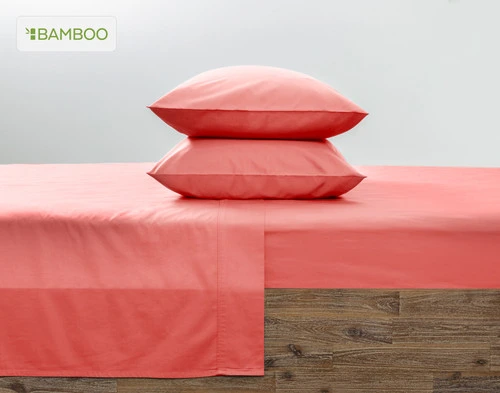 Two of our Bamboo Cotton Pillowcases in Hibiscus, a bright red-ish pink, stacked on top of each other on a coordinating pink bed.