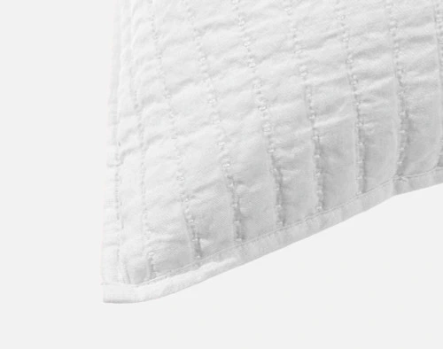 Gros plan sur le léger rebord du coin de notre housse de coussin carrée en coton lin en blanc.