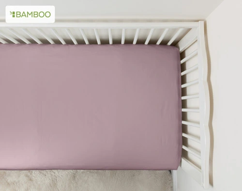 Vue de dessus de notre Bamboo Cotton Crib-Sized Fitted drap en Orchid s'adaptant parfaitement au matelas d'un lit d'enfant.