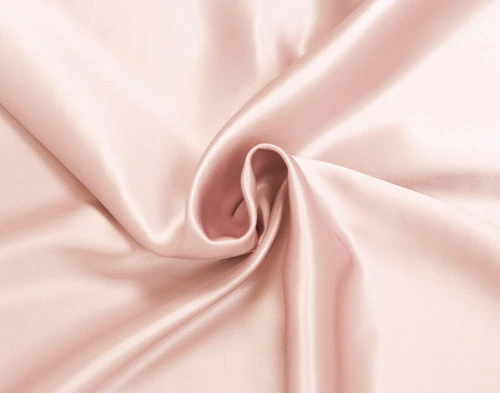 Gros plan sur une section torsadée de notre taie d'oreiller rose blush Pink Soie de mûrier pour mettre en valeur son tissu lisse et luxueux.