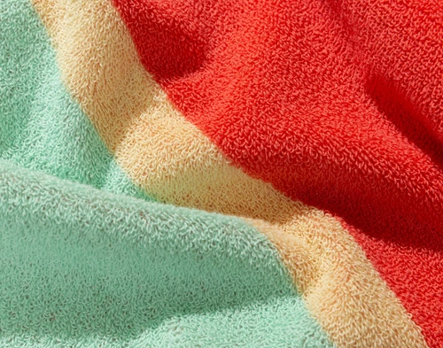 Gros plan sur le motif rayé rouge et vert de notre serviette de plage en coton Sunset.