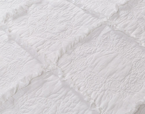 Gros plan sur les franges et la surface texturée de notre Rosalie Crib-Sized Cotton courtepointe.