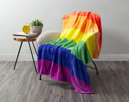 Notre traditionnel Pride Rainbow polaire Jeté  drapé sur une chaise dans un salon blanc.