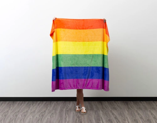 Vue de face d'une femme brandissant notre Pride Rainbow polaire Jeté  pour en montrer la longueur.