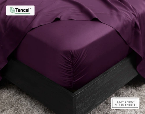 Gros plan sur le coin de notre BeechBliss TENCEL™ Modal Fitted drap en Plum qui s'adapte parfaitement à un matelas avec un drap plat drapé sur le dessus.