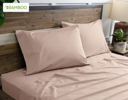 Deux de nos taies d'oreiller Bamboo Cotton en givré Berry Pink reposent sur un lit en bois avec draps.