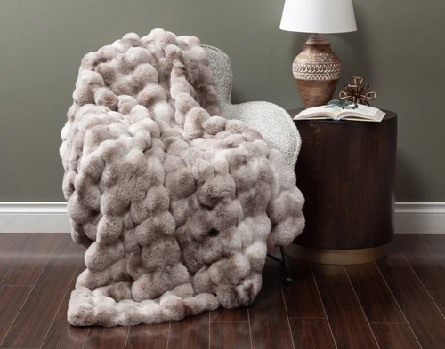 Vue de face de notre Bubble Faux Fur Jeté en Marled drapé sur un petit fauteuil dans un salon vert d'automne.