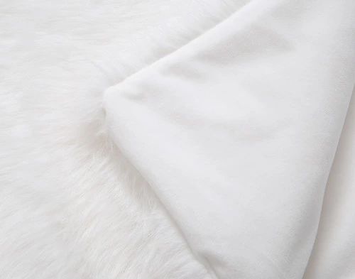 Close-up on the folded smooth reverse on the corner of our Polar Fur Throw in White.