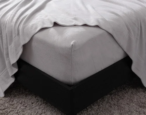 Close-up on the corner of our Cuddle Fleece Sheet Set in Granite with its fitted sheet wrapped around a queen mattress.
