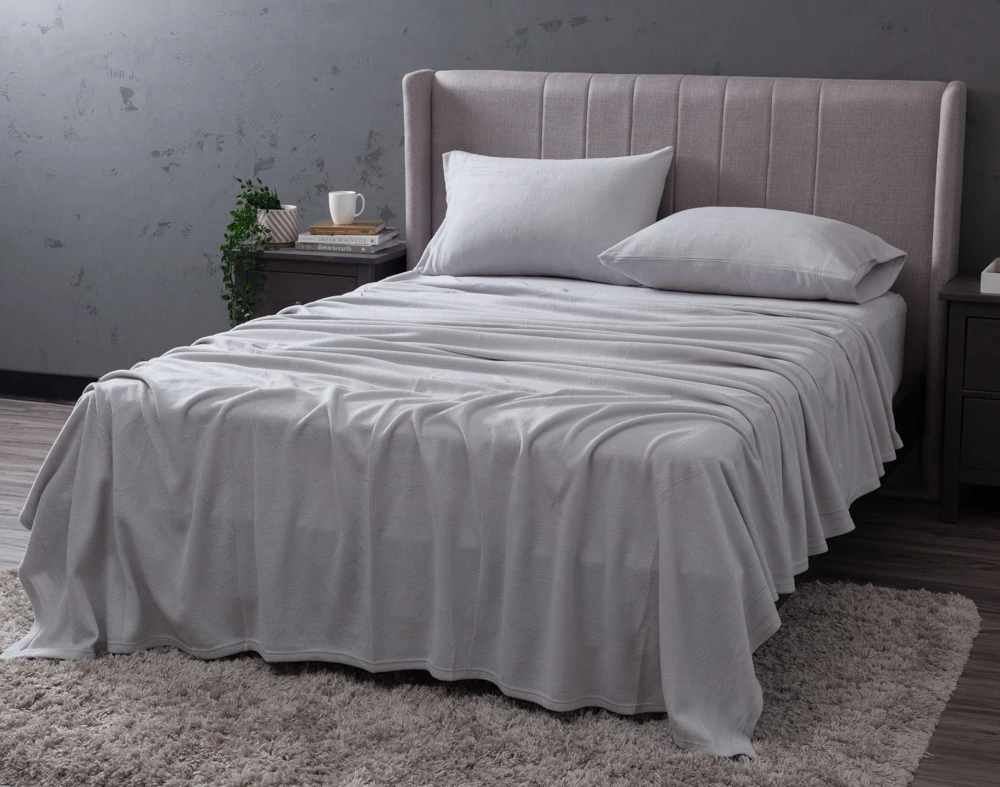 Angled view of our Cuddle Fleece Sheet Set in Granite fitted over a queen bed in a dark grey bedroom.