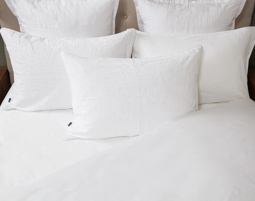 Vue du dessus de notre Chalkstone Pillow Sham reposant sur des oreillers coordonnés sur un lit blanc à moitié habillé.