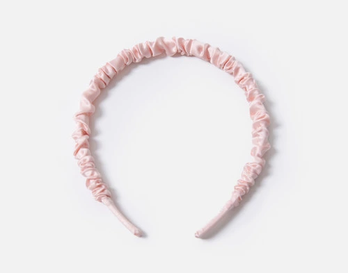 Vue de face de notre bandeau à cheveux Soie de mûrier Wrapped Hairband in rose blush reposant sur un fond blanc uni.