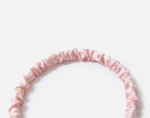 Gros plan sur le bord supérieur froncé de notre bandeau à cheveux Soie de mûrier Wrapped Hairband en rose blush.