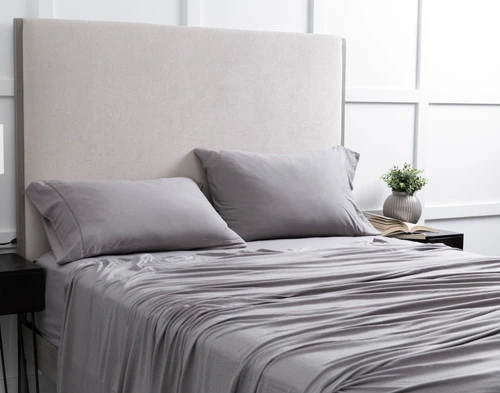 Vue en angle de notre Bamboo Cotton Jersey drap ensemble  en Grey habillé sur un lit simple dans une chambre blanche.