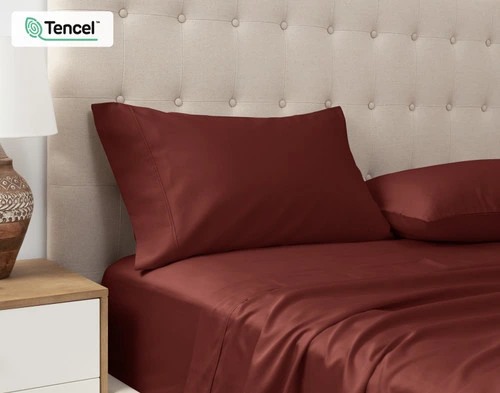 Vue en angle de nos Taies d'oreiller Eucalyptus Luxe TENCEL™ Lyocell en Marron posées contre la tête de lit d'un lit queen beige.