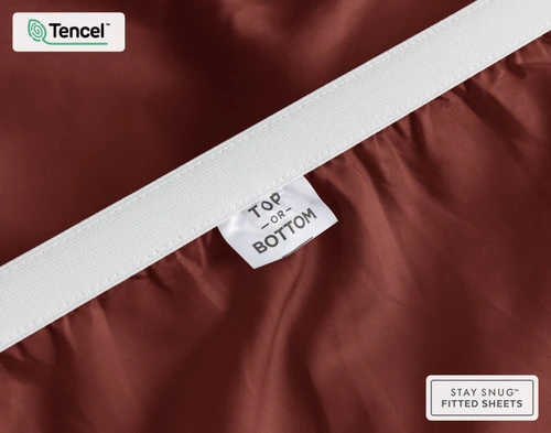 Gros plan sur le bord élastique étiré et l'étiquette indiquant "Top / Bottom" sur notre Eucalyptus Luxe TENCEL™ Lyocell Fitted drap en Maroon.