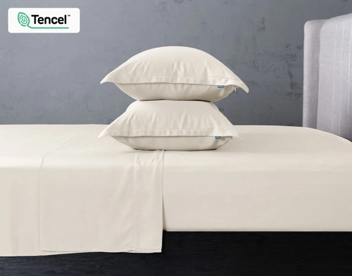 Vue de côté de deux oreillers BeechBliss TENCEL™ Modal en nuage empilés au centre d'un lit avec draps assorti.