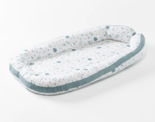 Angled view of our Baby Nest Bed in Teal featuring a foam border and organic cotton cover.