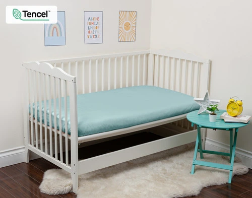 Notre Eucalyptus Luxe Crib-Size Fitted drap en Shoreline s'habille sur un petit matelas dans un lit ouvert.