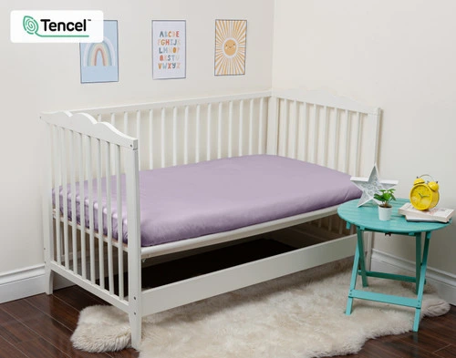 Notre Eucalyptus Luxe Crib-Size Fitted drap en Shoreline s'habille sur un petit matelas dans un lit ouvert.