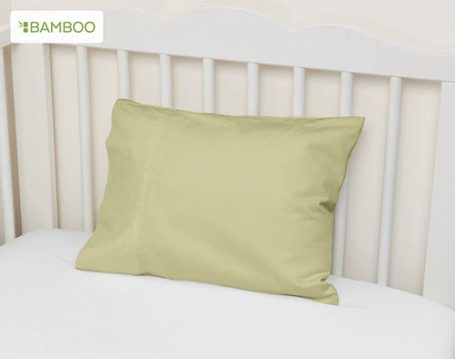 Vue de biais de notre taie d'oreiller Bamboo Cotton en orme, adossée au mur d'un lit d'enfant.