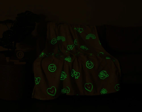 Notre Peace & Love Glow in the Dark polaire Jeté  s'assoit avec une légère lueur verte dans un salon sombre.