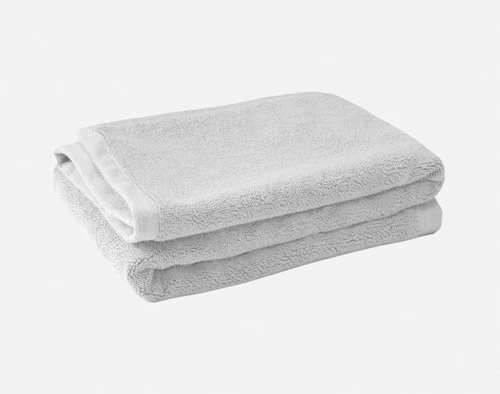 Pile pliée de notre tapis de bain en coton modal argenté sur un fond blanc uni.