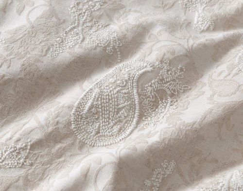 Gros plan sur un motif paisley brodé en forme de goutte d'eau sur la surface de notre housse de couette Prescott.