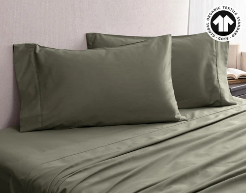 Angled view of our Organic Cotton Pillowcases in Alligator, resting on an empty bed with matching sheets.