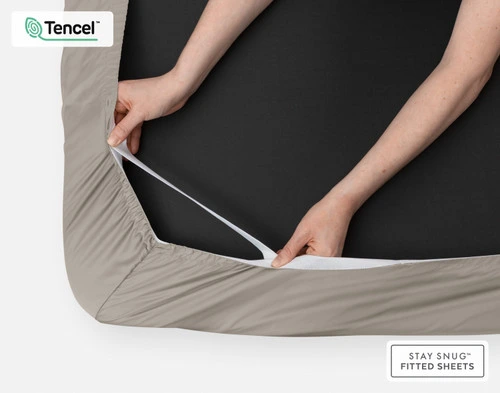 Bottom side of our BeechBliss TENCEL™ Modal Fitted Sheet in Grey Oak with two hands showing the Snug Fit elastics holding it tightly on the mattress.