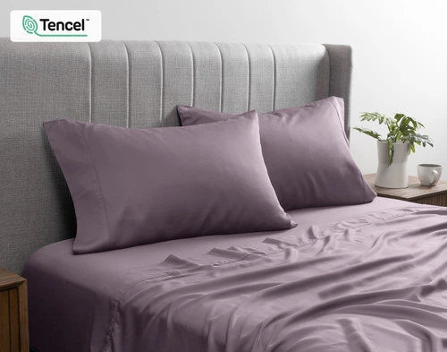 Front view of our BeechBliss TENCEL™ Modal Pillowcase in Purple Haze resting against a headboard in a bed with matching sheets.