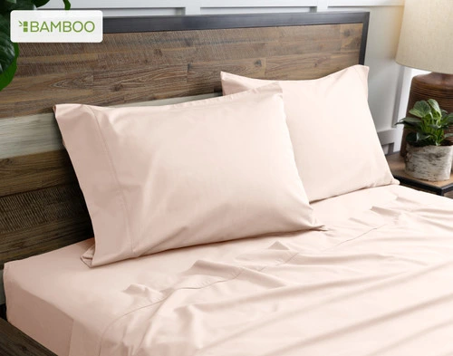 Two of our Bamboo Cotton Pillowcases in Rosemist resting on a wooden bed with coordinating sheets.