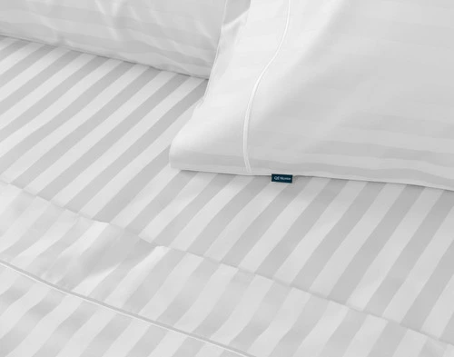 Close-up of the pillowcase, fitted sheet, and flat sheet of our White Luxor Egyptian Cotton Sheet Set fitted over a bed.