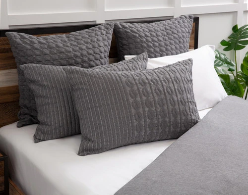 Angled view of our Soren Pillow Sham resting on a half-dressed white bed.