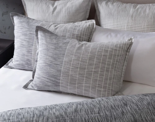 Angled view of our Halston Pillow Sham leaning against coordinating pillows.