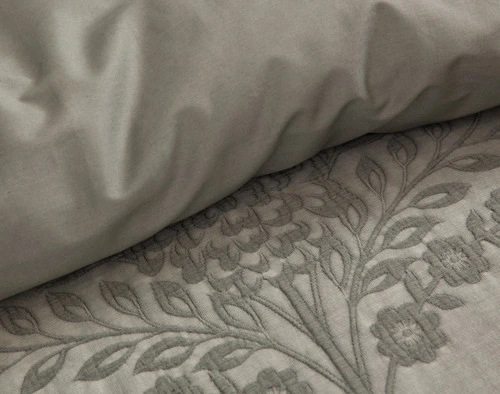 Close-up on the embroidered botanical motif and smooth backing of our Raintree Duvet Cover Set.