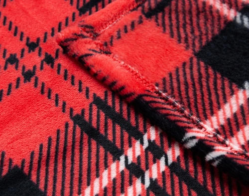 Close-up of the soft fleece surface and plaid pattern on the corner of our Carmine Plaid Throw.