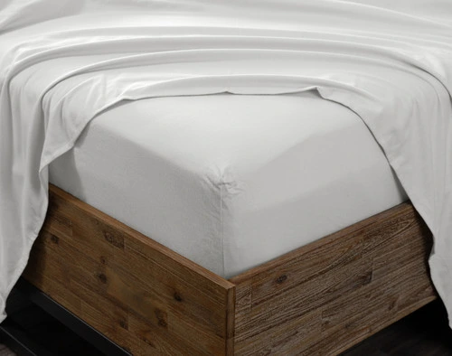 Close-up of a mattress corner dressed with a fitted sheet from our Nickel Organic Flannel Cotton Sheet Set, with a flat sheet draped over top.